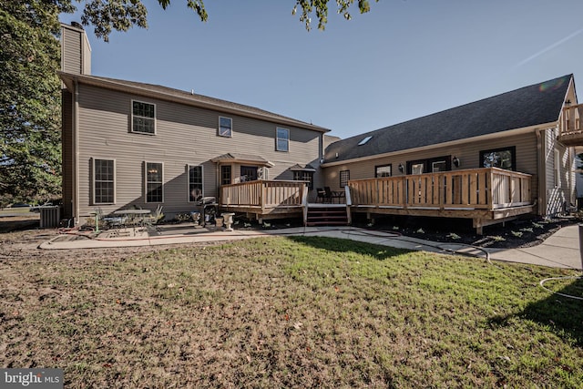 rear view of property with a deck, a patio, and a lawn