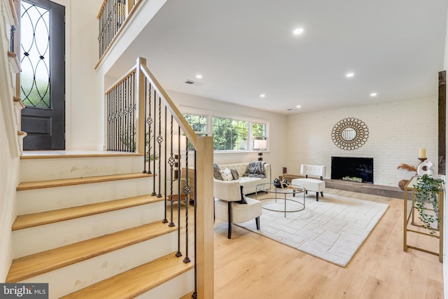 living room featuring brick wall and light hardwood / wood-style floors