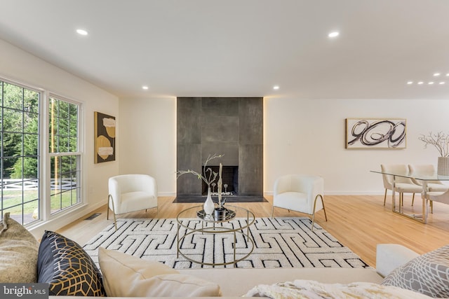 living room featuring light hardwood / wood-style flooring and a tiled fireplace