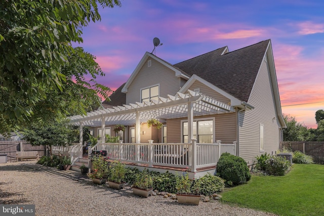 back house at dusk featuring a yard and a pergola