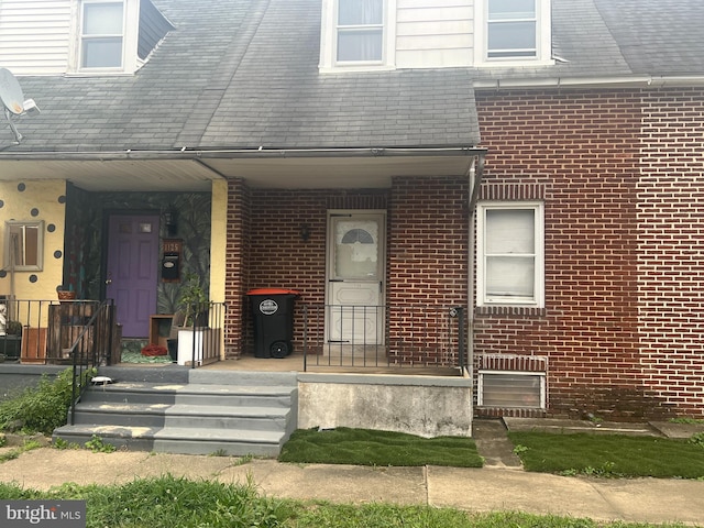 entrance to property with brick siding and a porch