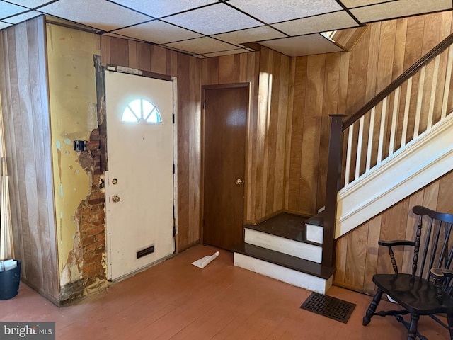 entryway featuring wooden walls, a drop ceiling, and wood-type flooring