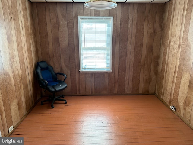 unfurnished room featuring wooden walls and light hardwood / wood-style floors