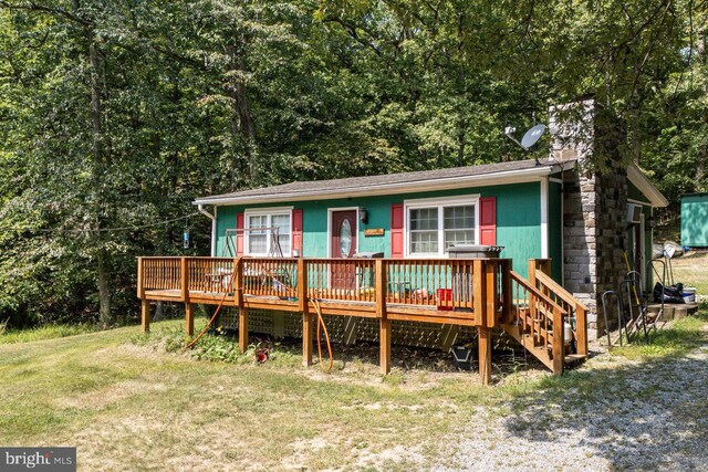 rear view of property featuring a lawn and a wooden deck