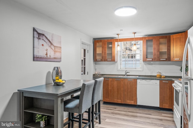 kitchen featuring pendant lighting, white appliances, backsplash, and light hardwood / wood-style floors