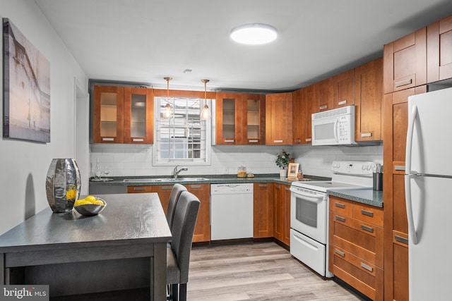 kitchen featuring light wood-type flooring, white appliances, backsplash, sink, and hanging light fixtures