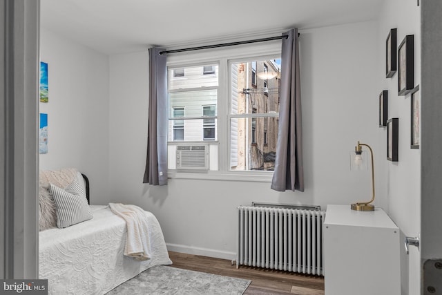 bedroom with radiator heating unit, multiple windows, and dark hardwood / wood-style flooring