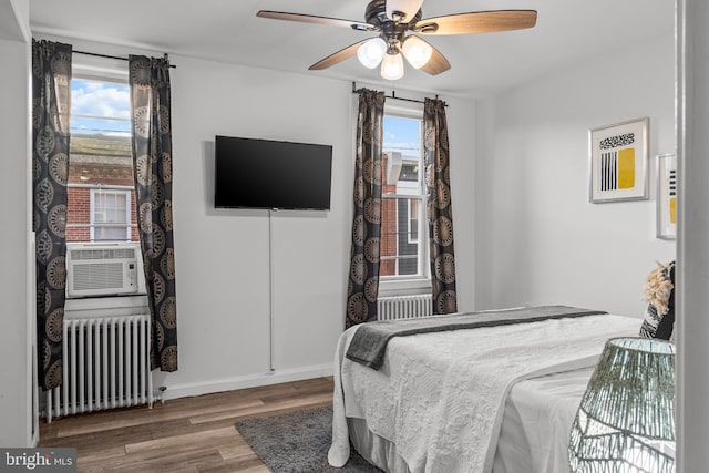 bedroom featuring radiator heating unit, multiple windows, hardwood / wood-style floors, and ceiling fan