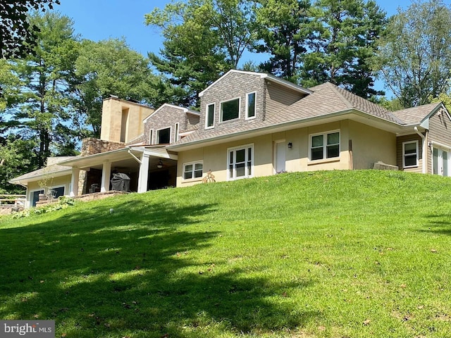 view of front facade featuring an attached garage, roof with shingles, a front yard, and stucco siding