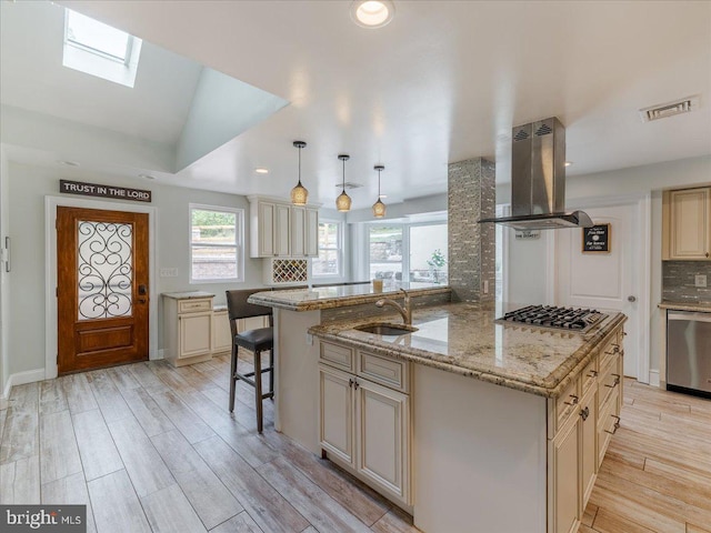 kitchen with island exhaust hood, hanging light fixtures, cream cabinetry, decorative backsplash, and appliances with stainless steel finishes