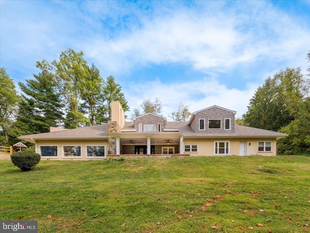 back of property featuring ceiling fan, a yard, and a chimney