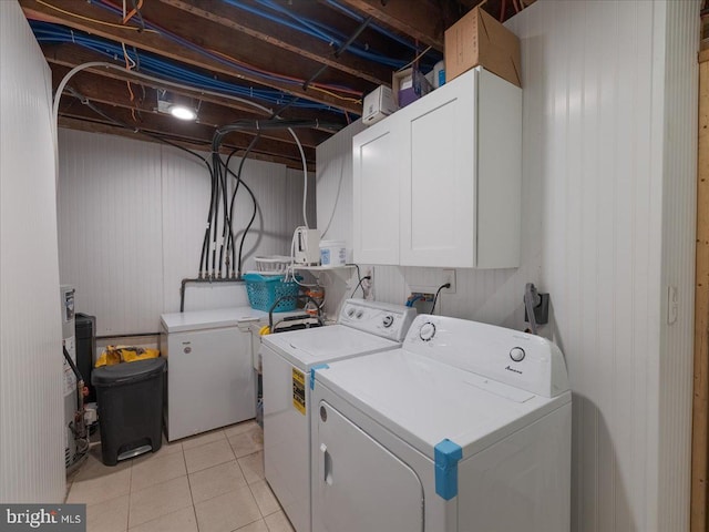 clothes washing area featuring separate washer and dryer, light tile patterned flooring, and cabinets