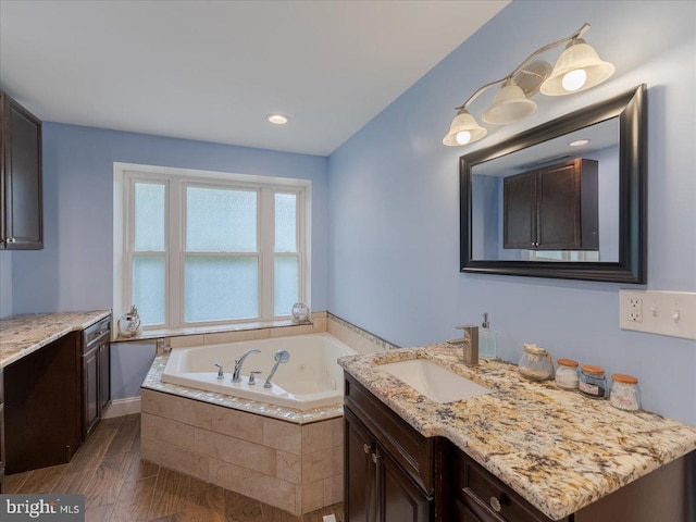 bathroom featuring wood finished floors, vanity, and a bath