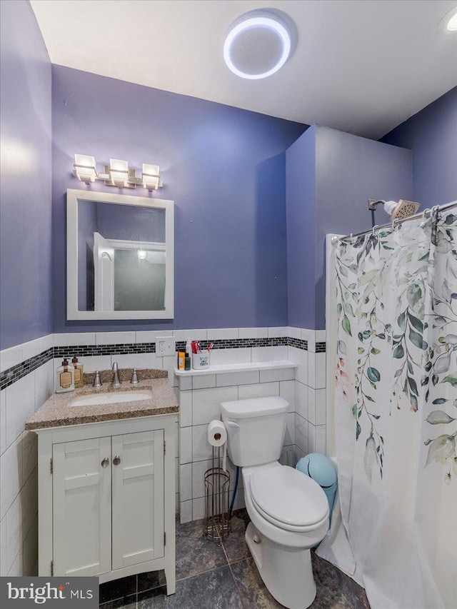 bathroom with tile walls, vanity, and toilet