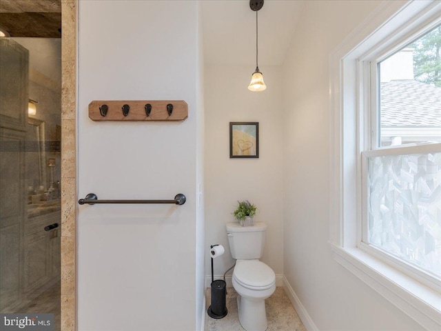 bathroom with toilet, a shower stall, and baseboards