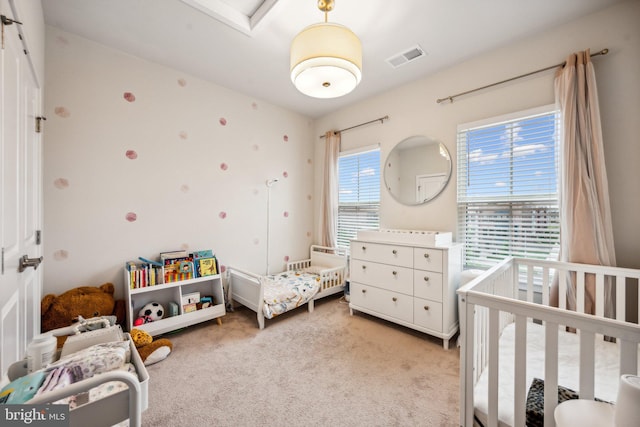 bedroom with light colored carpet and a nursery area