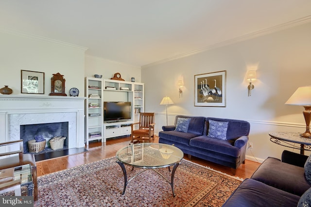 living room with ornamental molding, a high end fireplace, and wood-type flooring