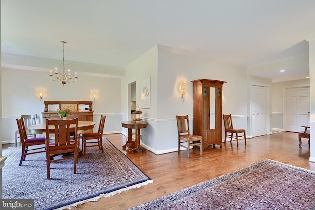 dining room featuring an inviting chandelier, crown molding, baseboards, and wood finished floors