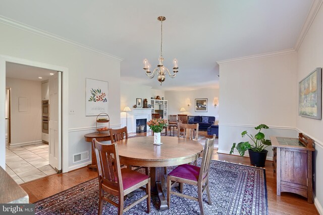 dining room featuring a chandelier, light hardwood / wood-style floors, and crown molding