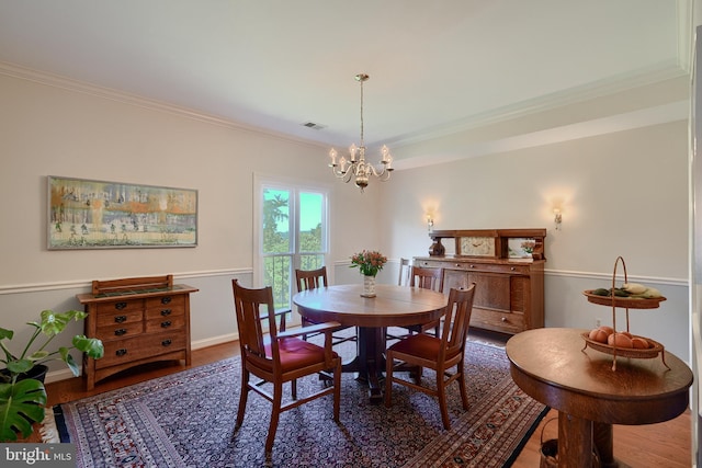 dining space with ornamental molding, dark wood-type flooring, and a notable chandelier