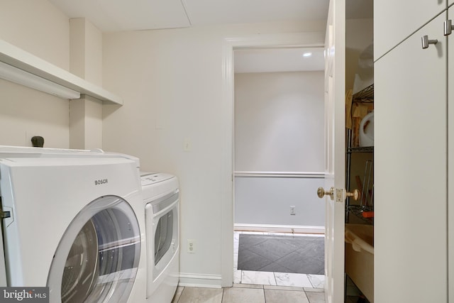 clothes washing area featuring laundry area, baseboards, light tile patterned flooring, and washing machine and clothes dryer