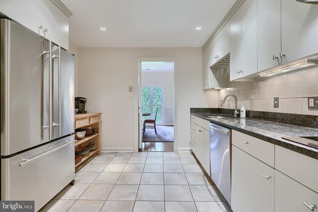 kitchen featuring backsplash, light hardwood / wood-style floors, stainless steel appliances, sink, and white cabinetry