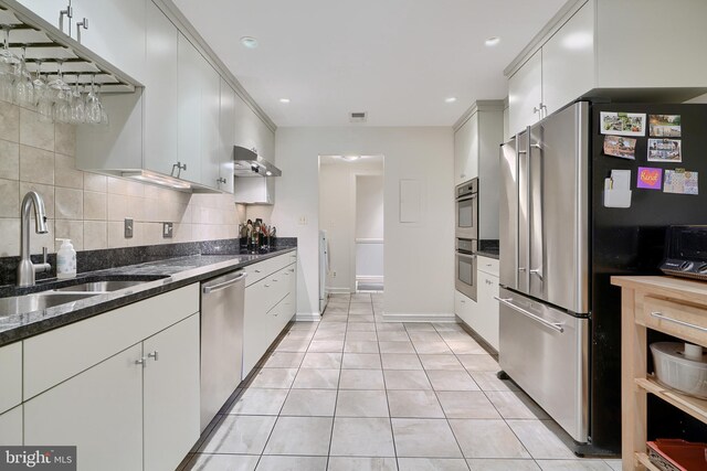 kitchen with backsplash, appliances with stainless steel finishes, sink, dark stone counters, and light tile patterned flooring