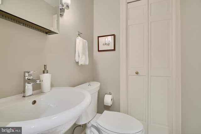 bathroom with toilet, a closet, and a sink