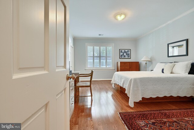 bedroom featuring light wood-type flooring and crown molding