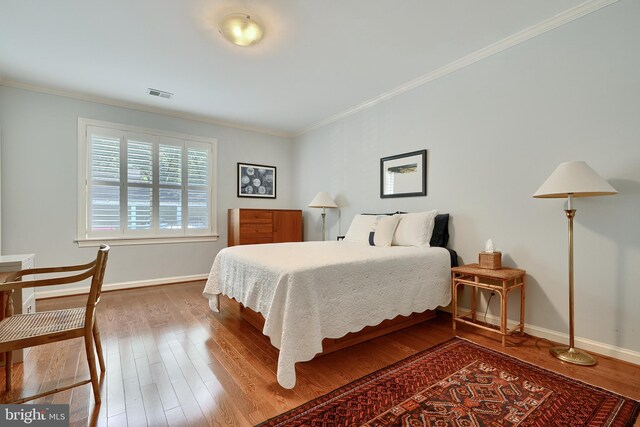 bedroom with hardwood / wood-style floors and ornamental molding