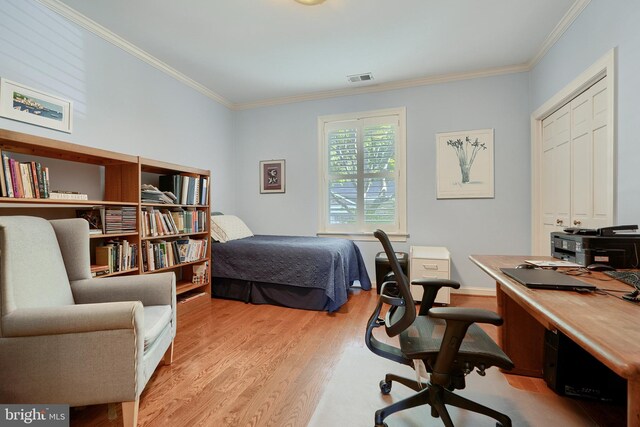 bedroom with light wood-type flooring, ornamental molding, and a closet