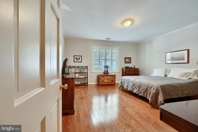 bedroom featuring crown molding and light hardwood / wood-style flooring