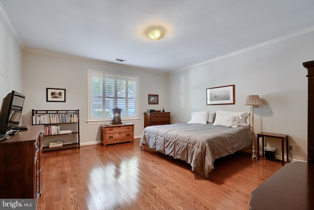 bedroom featuring baseboards, crown molding, visible vents, and wood finished floors