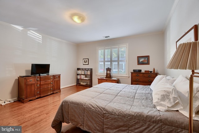 bedroom featuring light wood-type flooring, baseboards, visible vents, and ornamental molding