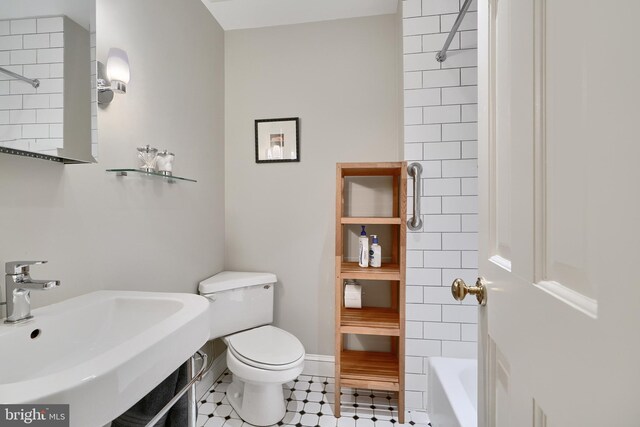 full bathroom with tile patterned flooring, toilet, tiled shower / bath, and sink