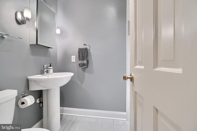 half bath featuring toilet, baseboards, and wood finished floors