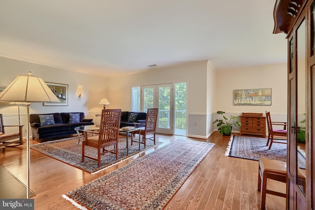 living room featuring french doors, crown molding, and light hardwood / wood-style flooring