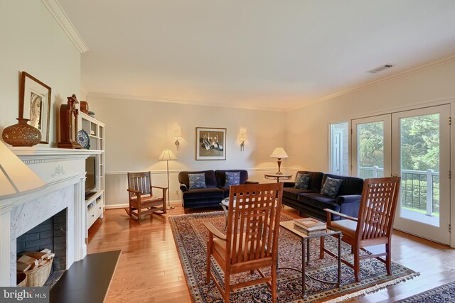 living room featuring light hardwood / wood-style flooring, ornamental molding, and a fireplace