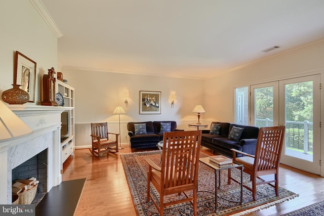 living room featuring a fireplace, wood finished floors, visible vents, french doors, and crown molding