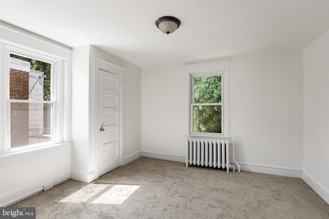 unfurnished bedroom featuring a closet, radiator, and light carpet