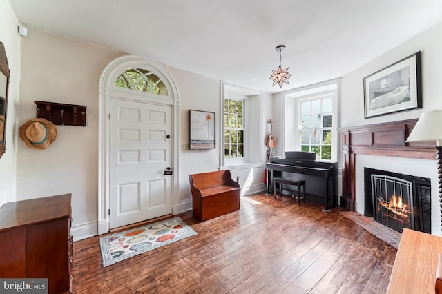 foyer featuring baseboards, a lit fireplace, and hardwood / wood-style flooring