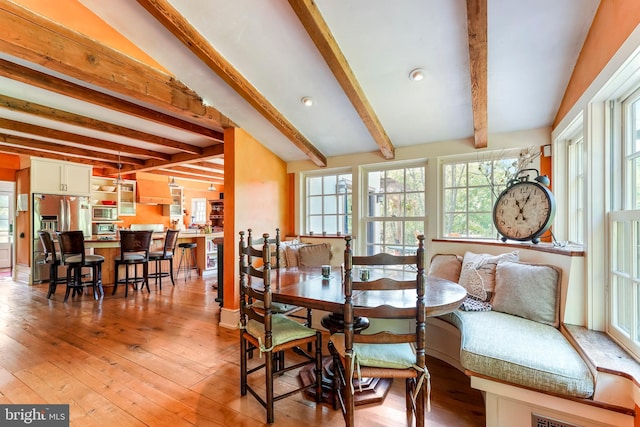 dining room featuring light hardwood / wood-style floors and beamed ceiling