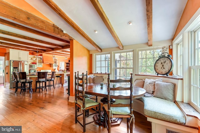dining space featuring beamed ceiling and light wood-style flooring