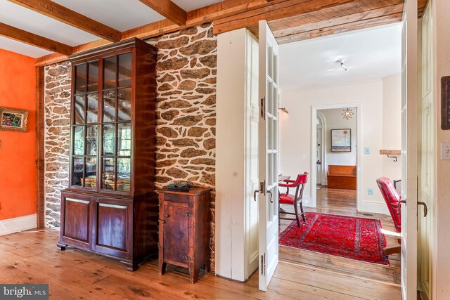 hallway featuring wood-type flooring and beamed ceiling