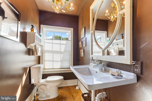 half bath featuring an inviting chandelier, toilet, baseboards, and wood finished floors