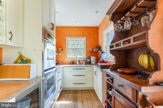 kitchen featuring light wood-type flooring, white cabinets, and stainless steel double oven