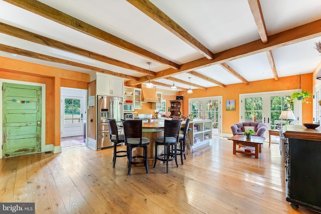 dining room featuring beamed ceiling, light hardwood / wood-style flooring, and french doors