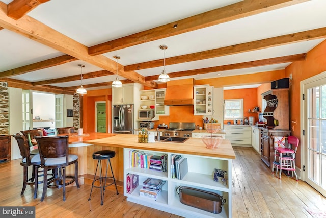 kitchen with appliances with stainless steel finishes, light wood-type flooring, wood counters, and pendant lighting