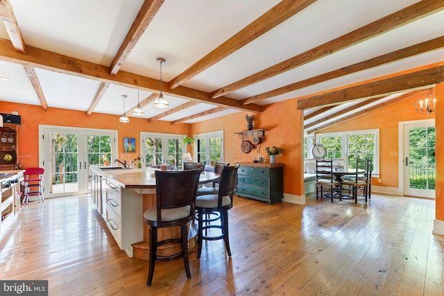 kitchen with a kitchen island with sink, a wealth of natural light, white cabinetry, and decorative light fixtures