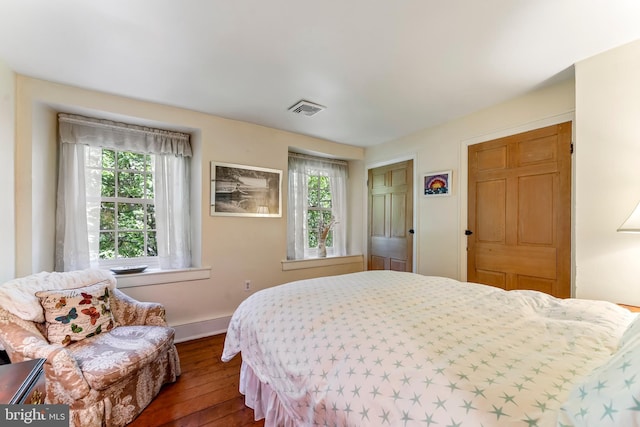 bedroom with multiple windows, visible vents, baseboards, and dark wood-type flooring